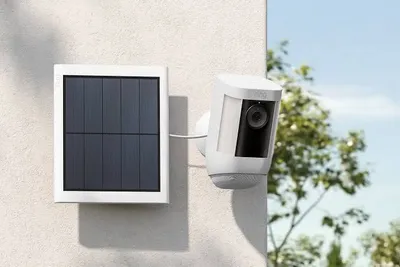 Wireless Ring security camera with a solar panel mounted on a stucco exterior wall